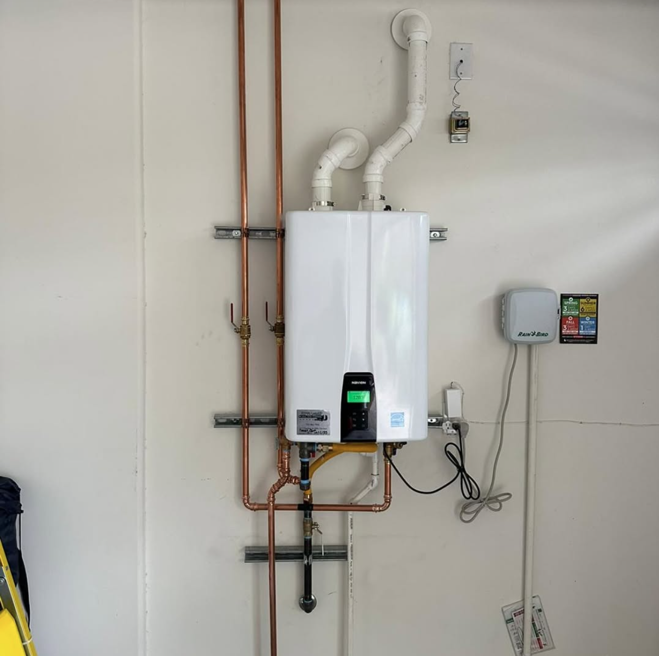 Tankless water heater mounted on a wall with copper pipe connections