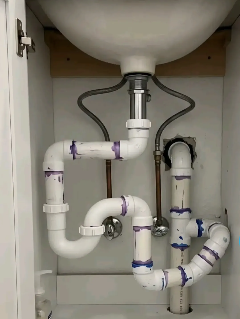 Close-up of a sink drain P-trap and plumbing connections